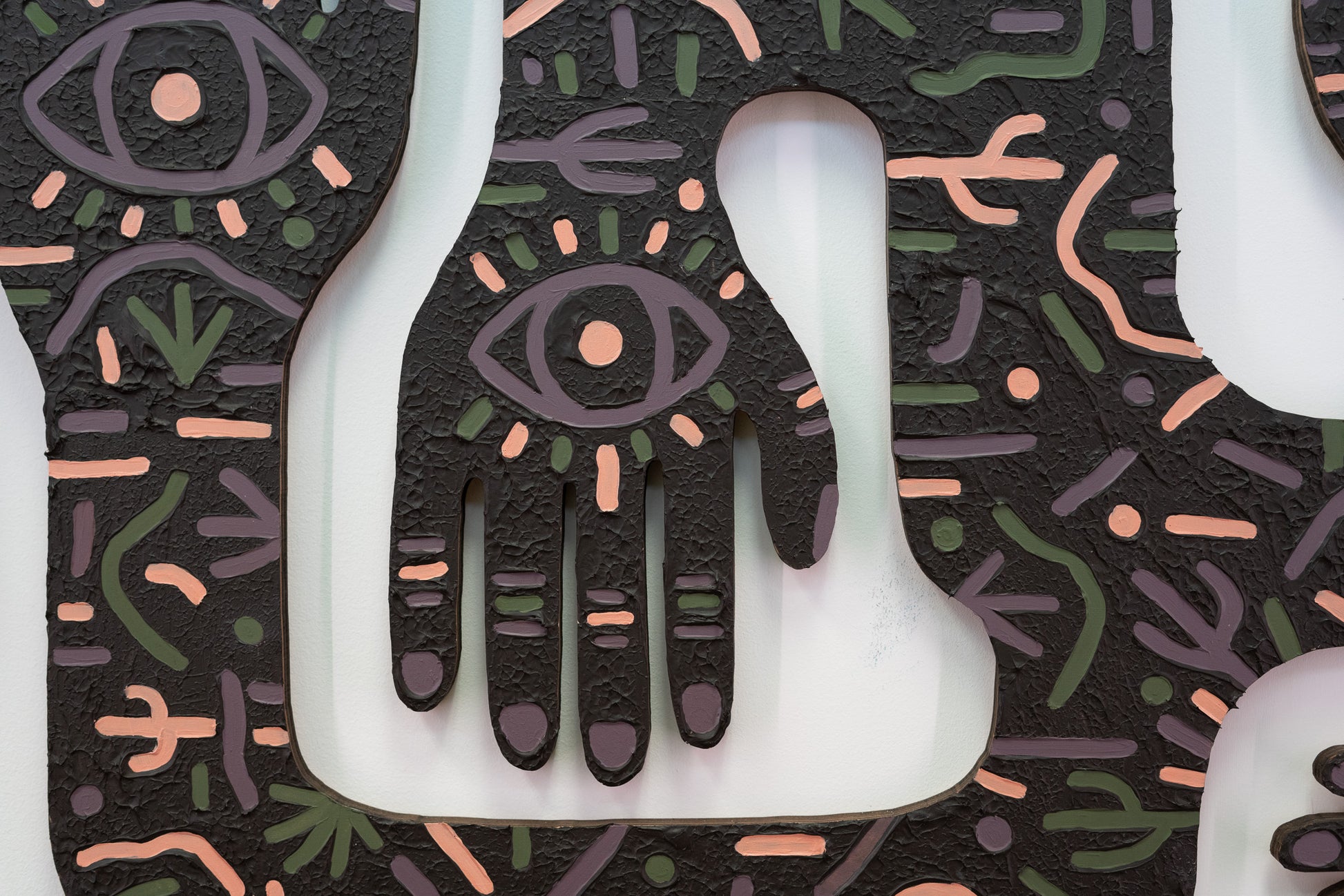 A close up of a laser cut  art work. The art work has high texture and eyes on the hands